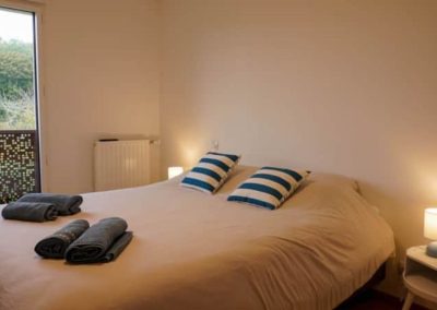 Chambre avec grand lit double, lampes de chevet et coussins rayés bleus