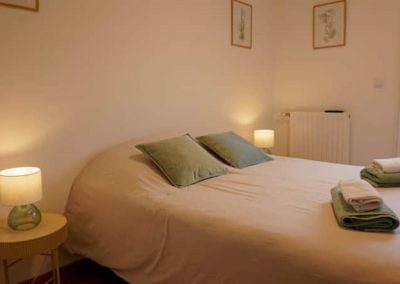 Chambre double avec coussins verts et décoration végétale