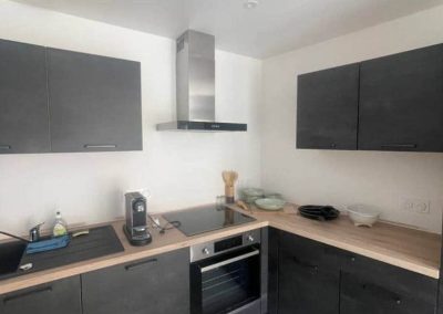 Cuisine noire et bois avec four, plaques et hotte