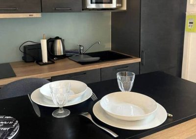 Cuisine noire et bois avec coin repas pour deux personnes.