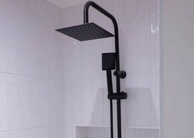 Douche à l'italienne avec colonne noire sur carrelage blanc