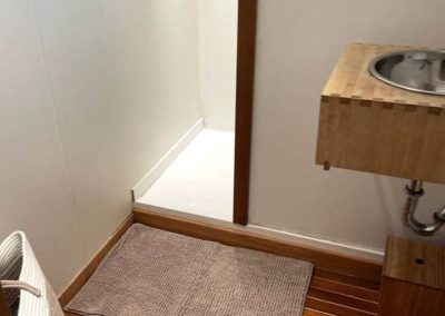 Douche ouverte et vasque en bois dans une salle d’eau épurée