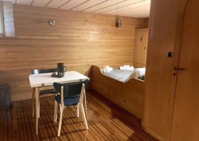 Vue d’ensemble du studio avec lit et table dans un décor boisé