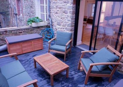 Terrasse en bois avec mobilier de jardin en bois et coussins verts